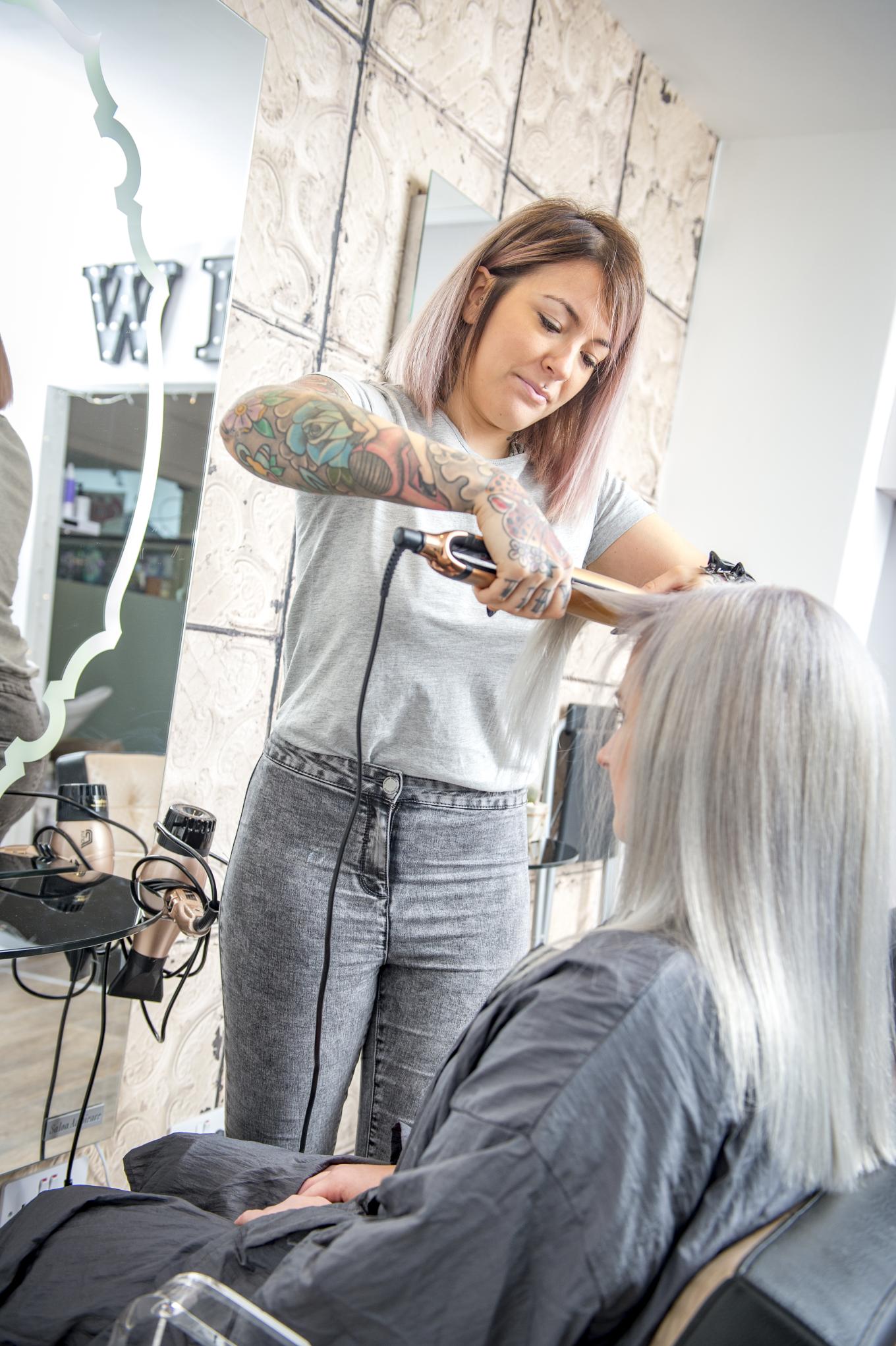 A hairdresser straightening a clients hair 